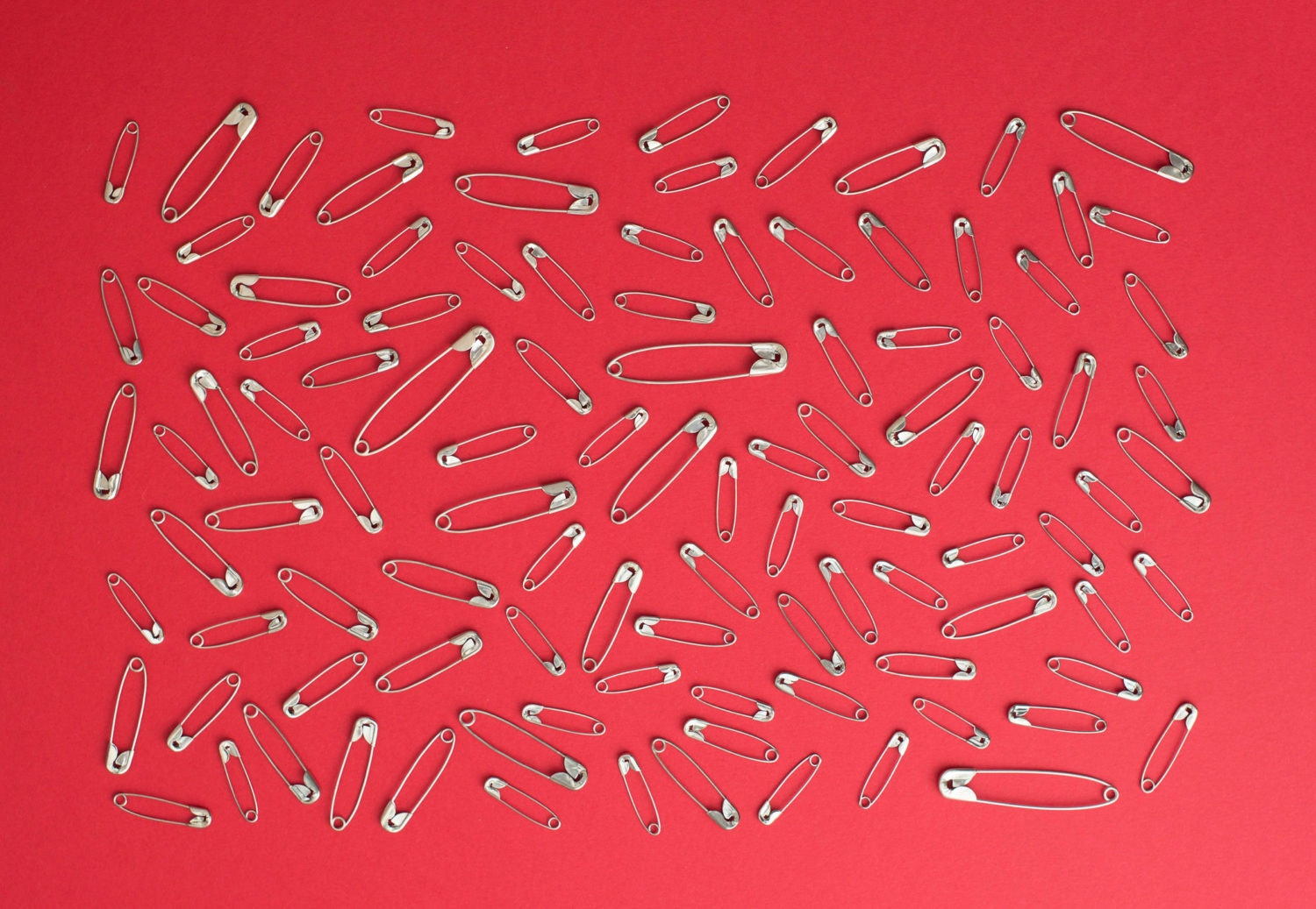 lots of safety pins over red background