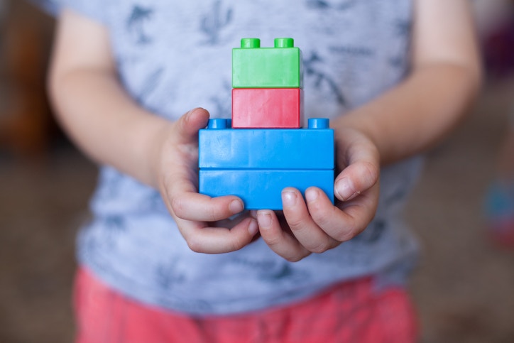young boy playing with his building blocks holding a finished creation in his hands