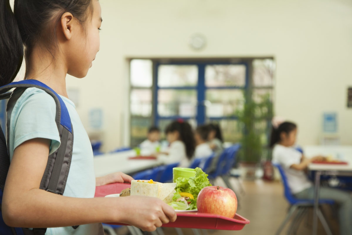 Girl holding tray with healthyfood at school canteen