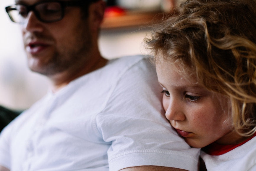 dad with a white shirt reading  to a child who is looking