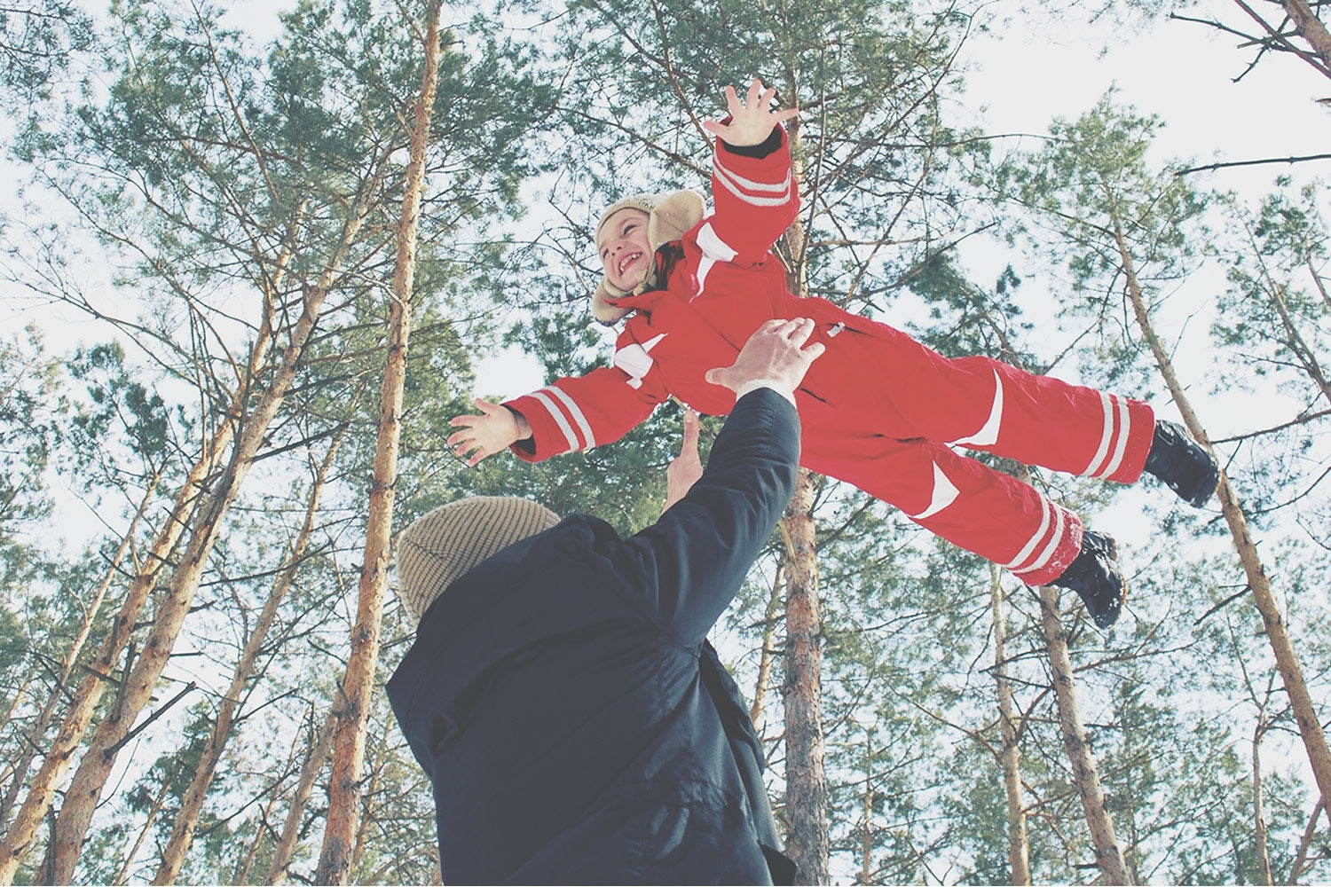 person tossing a young child in the air playing around