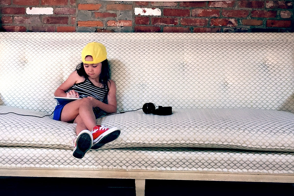 girl setting on white couch with looking at a tablet