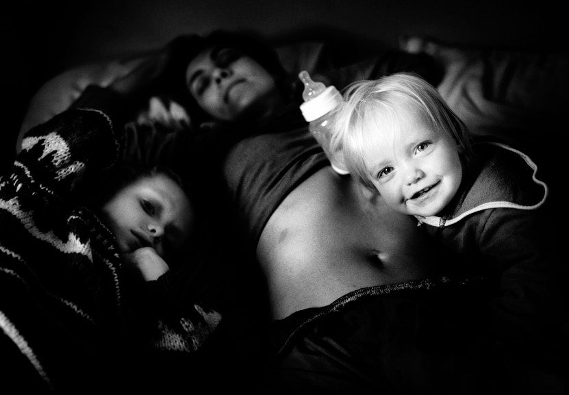 child lying on top of mother holding  feeding bottle