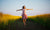 Young  woman jumping in the middle of a field with yellow flowers