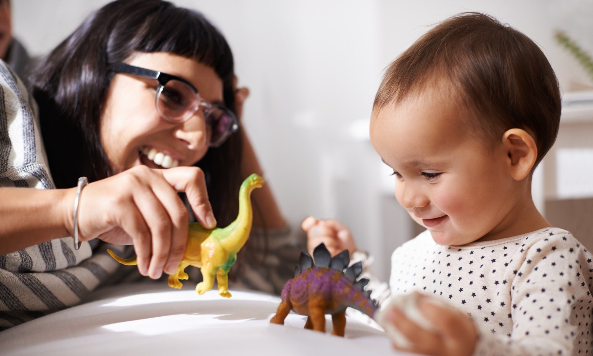 mom and child playing with colorful toy dinosaurs