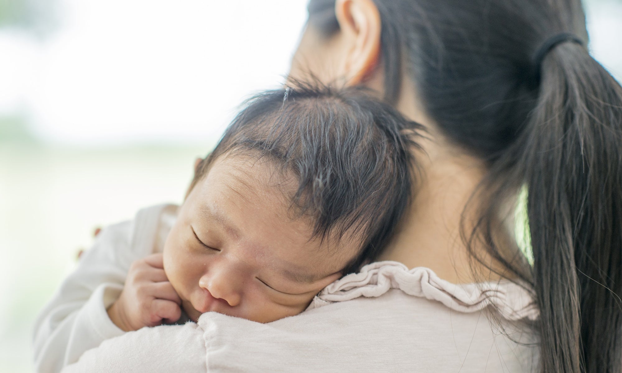 mother holding baby resting on shoulder