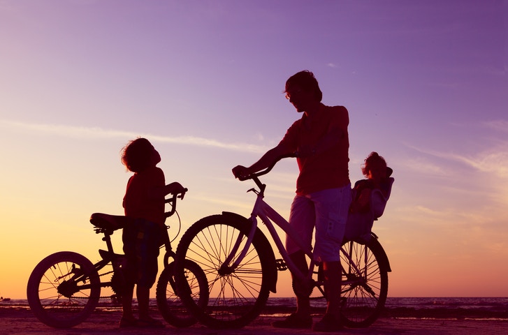 Father riding a bicycle with a child seat and a little boy riding a bicycle