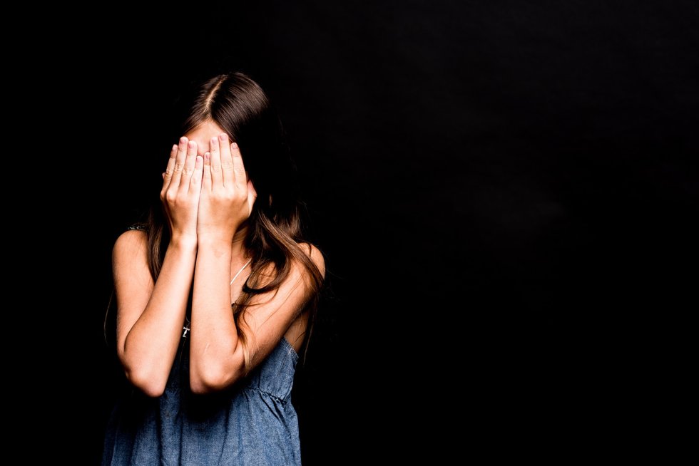 young girl covering her face with hands