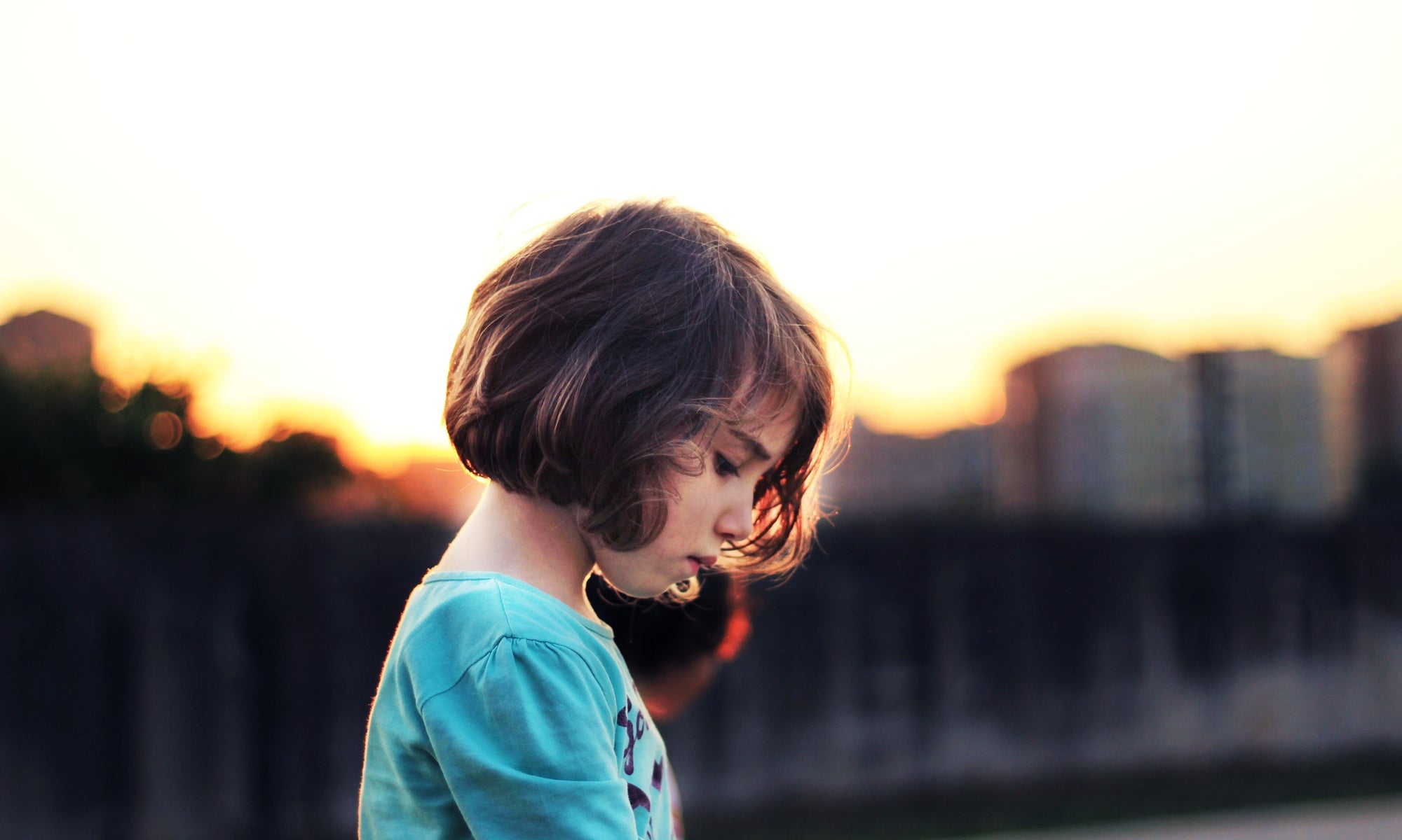 sad little girl standing on the road at asunset time