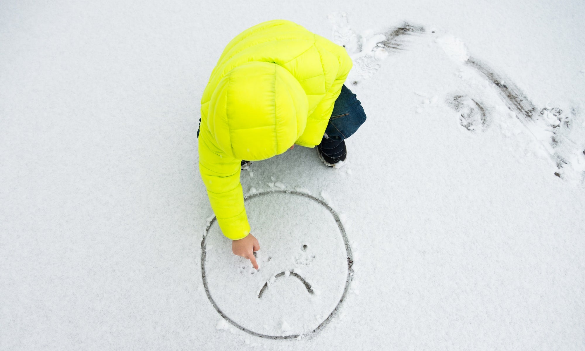 A child making sad emoji in snow