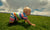 baby crawling on green grass with blue sky and clouds