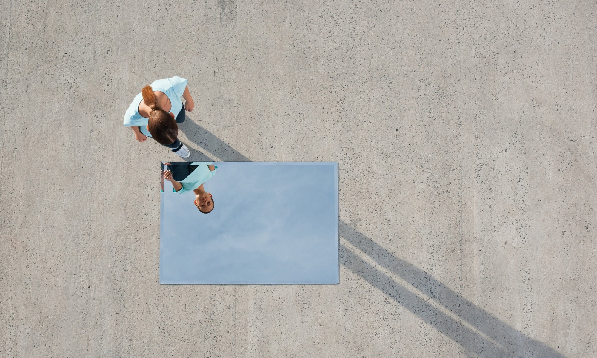 women on ground look at a mirror that is on the ground