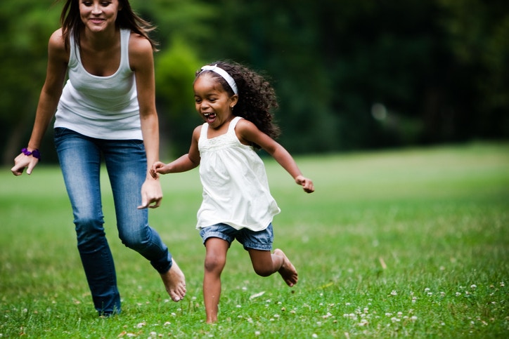 a girl in white dress playing with a young lady in a field