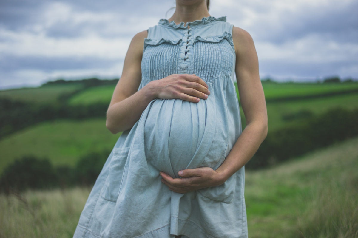 pregnant women support the stomach by hand and bright nature