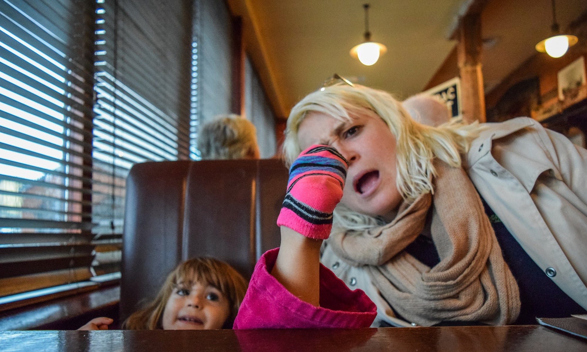 mother looking at  her little girl's sock and sitting on the cafe