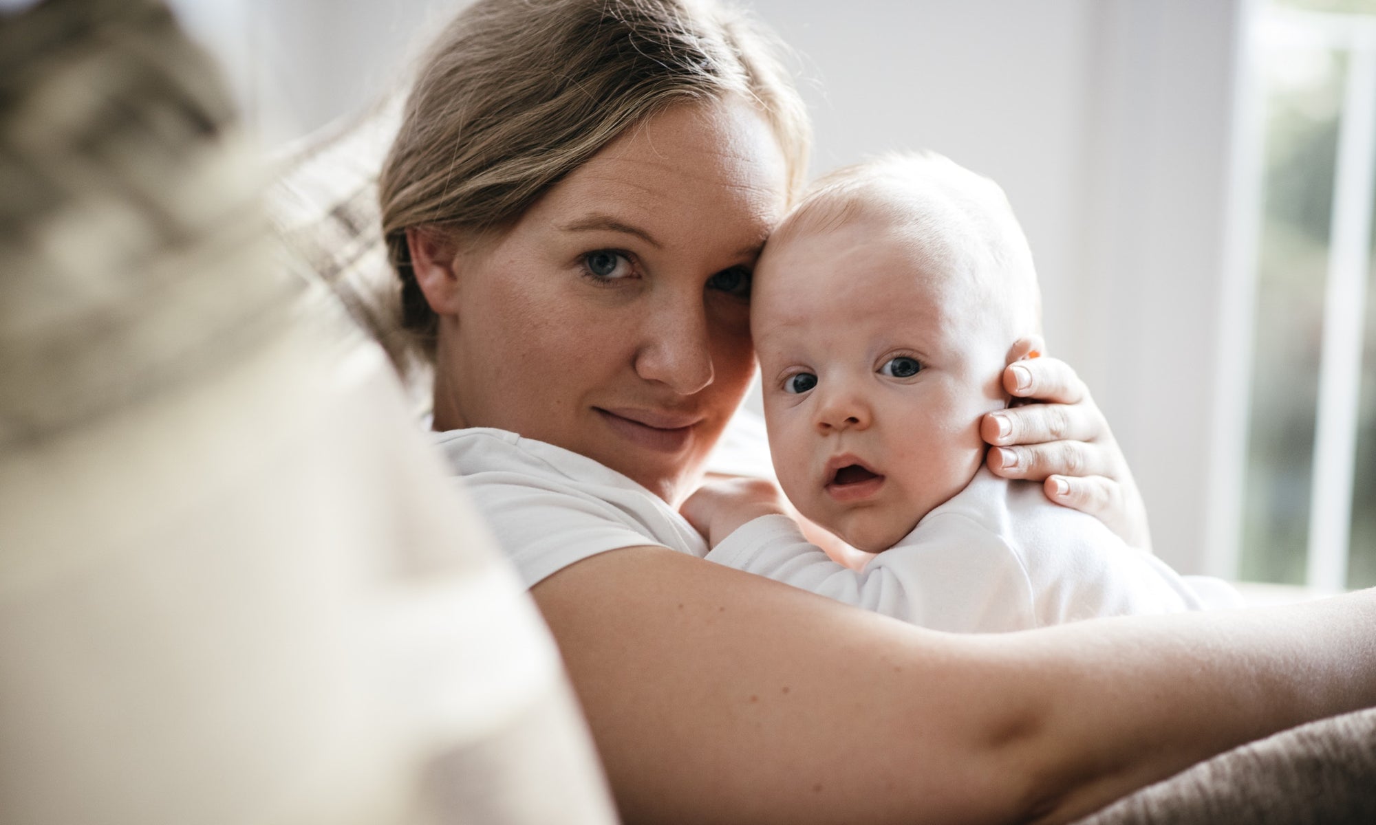 Surprised baby is lying on his mother's chest