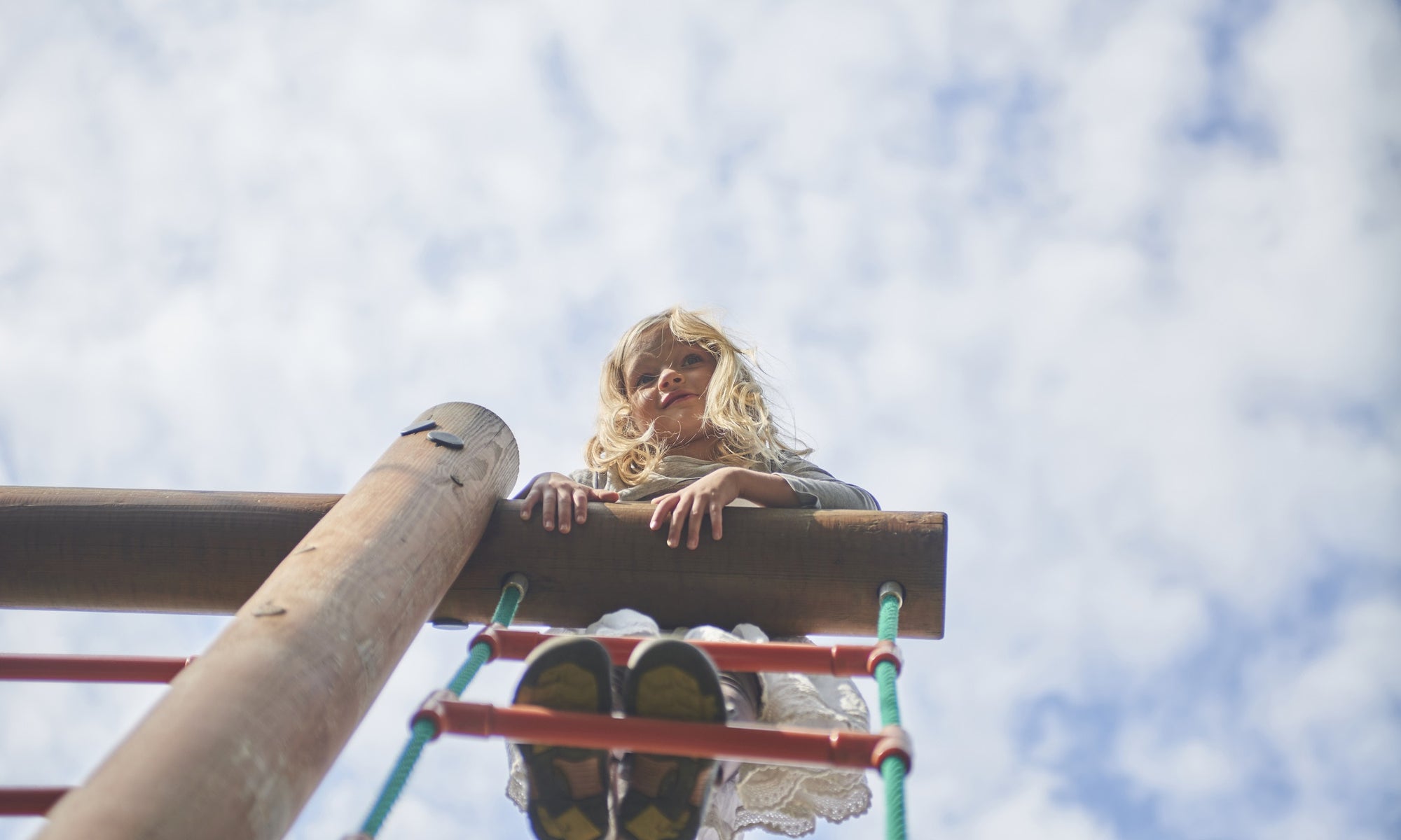 Young girl standing at top of ladder in playground