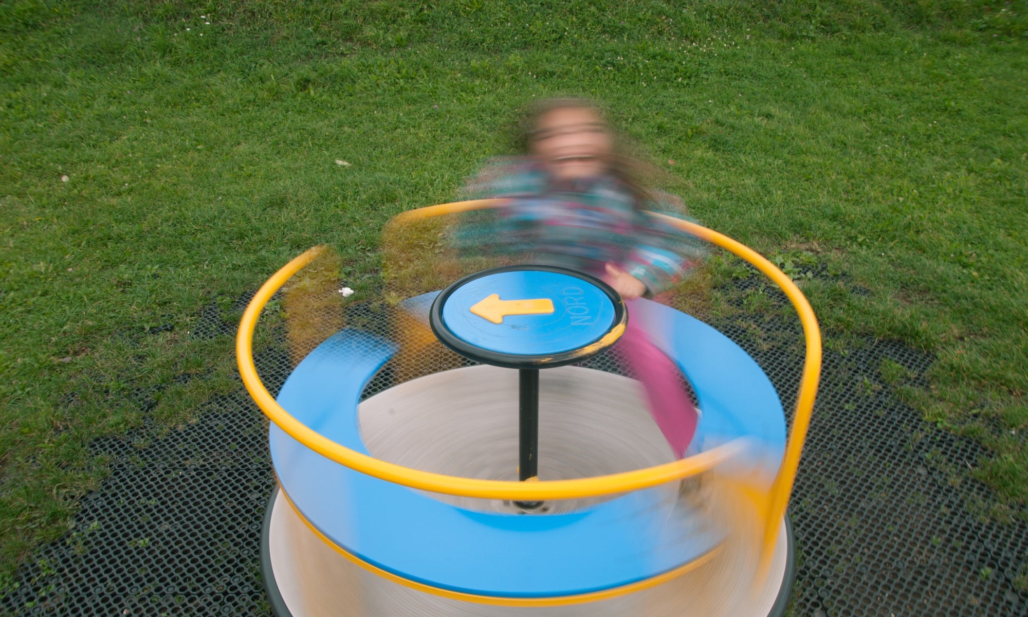 child spinning on playground roundabout