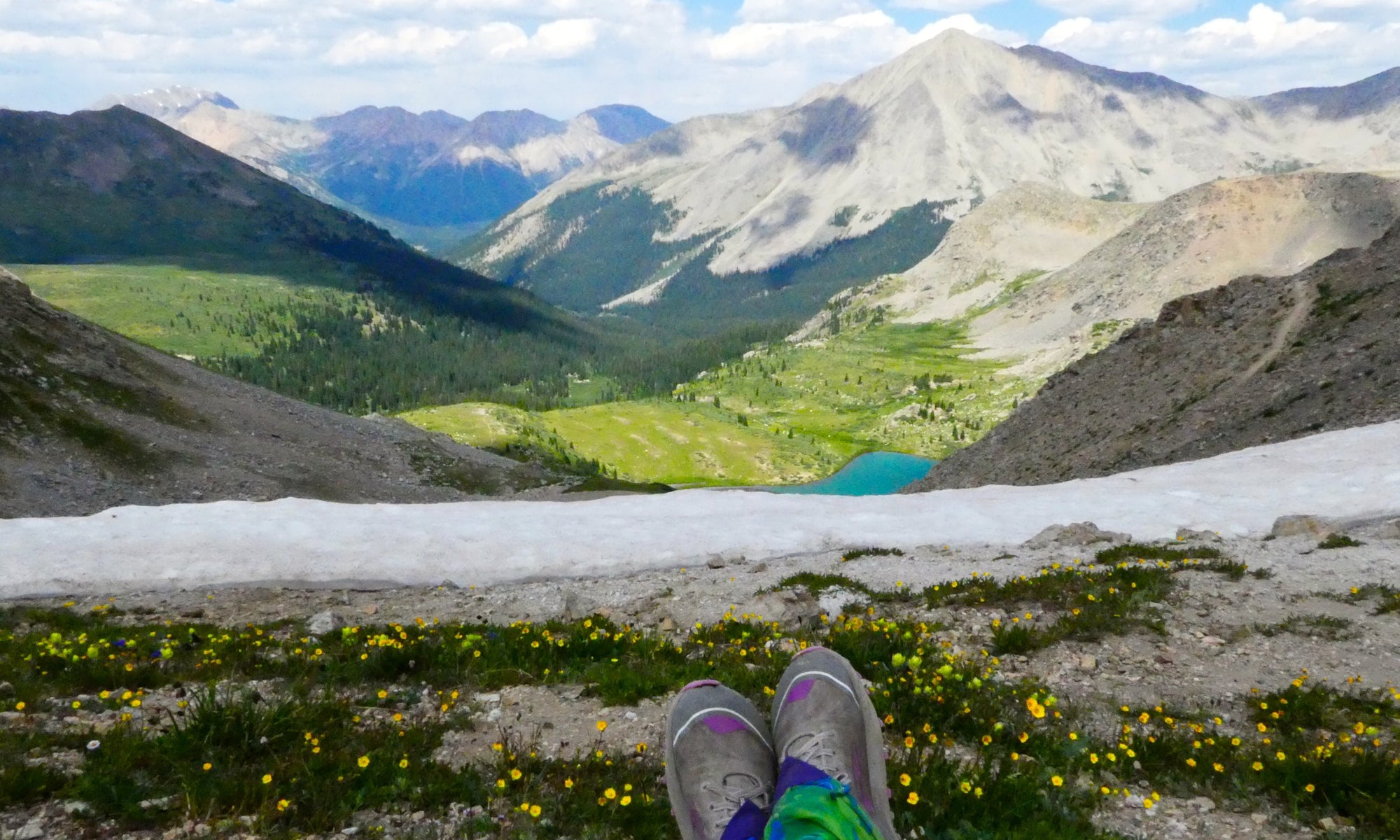 Person sitting on a high mountain top with first person perspective view, legs in focus