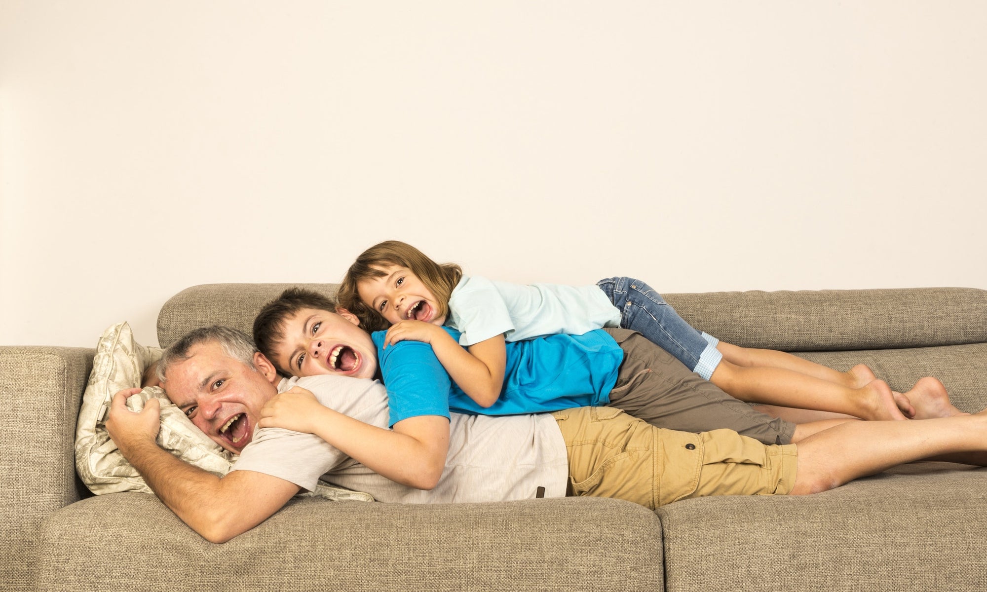 Father,son and daughter lying on top of each other 