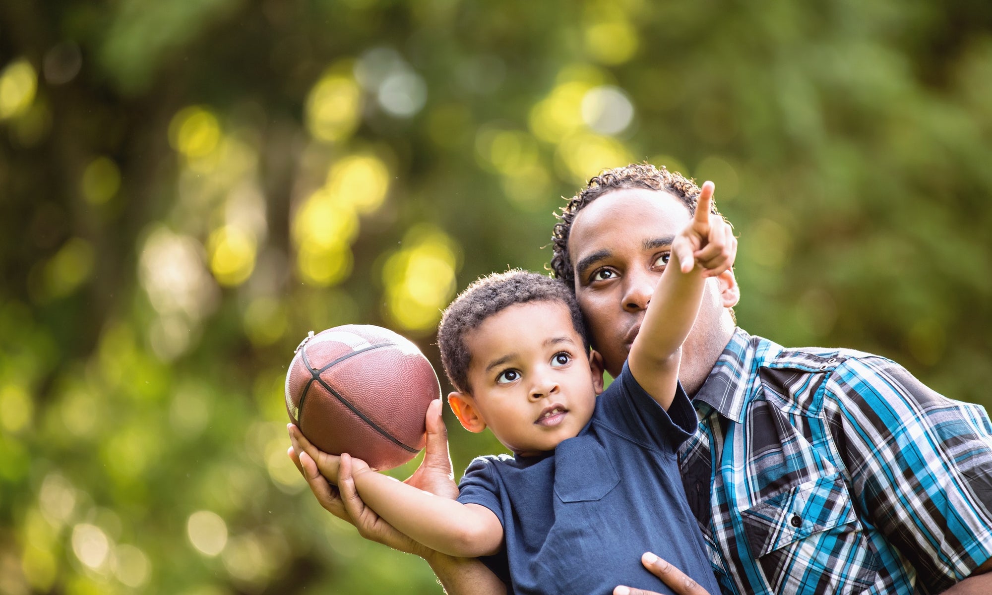 A kid is showing something to his father by holding a soccer