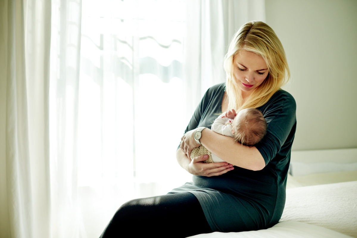 Mother holding her child in arms, in a white room