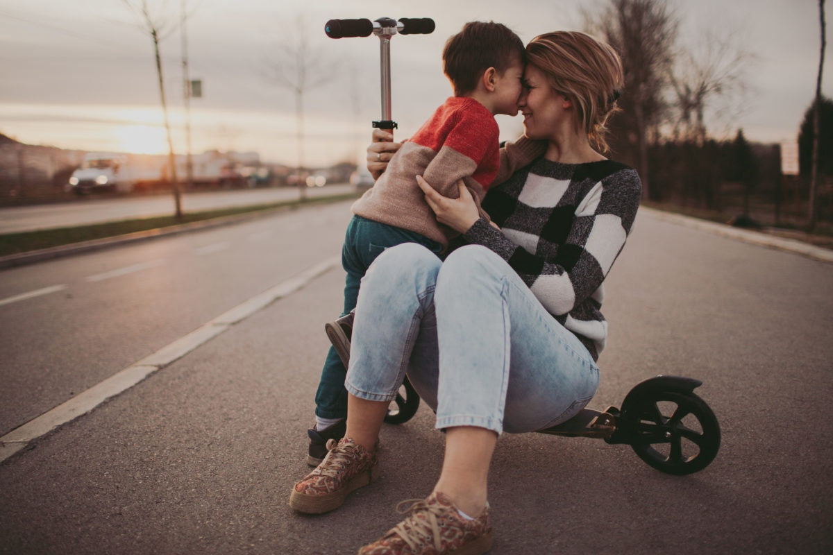 Mother sitting on an electric scooter with son next to her