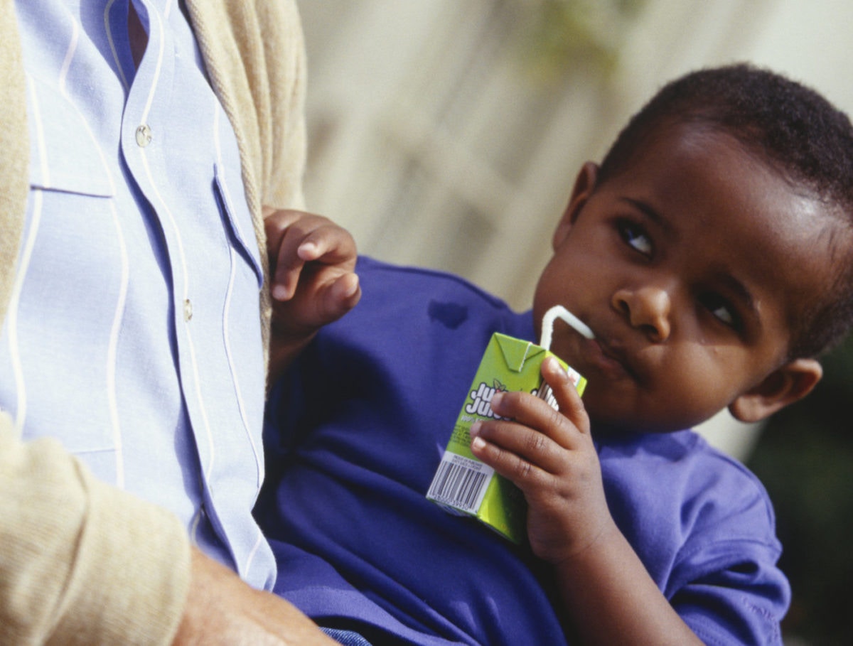 A kid is drinking juice by seeing his parent