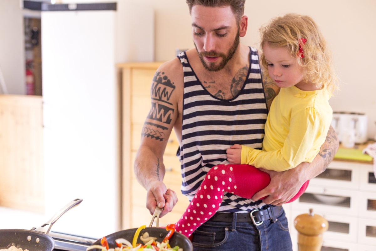 Cooking father holding small daughter in his arms