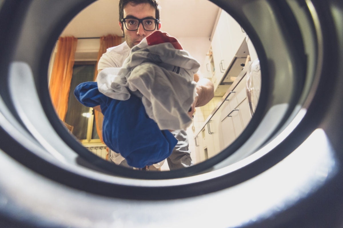 Man putting clothes into washing machine