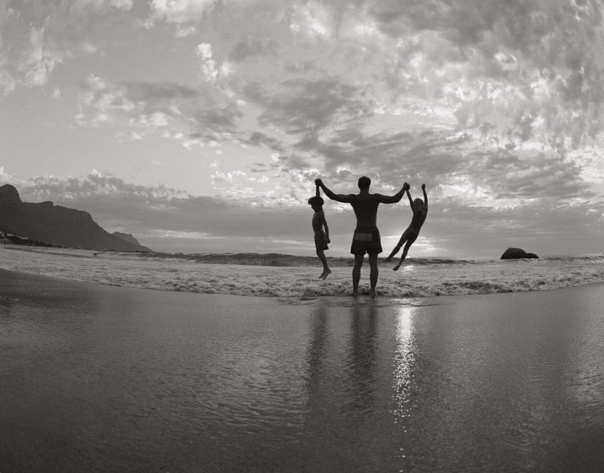 father and his two children playing on the beach