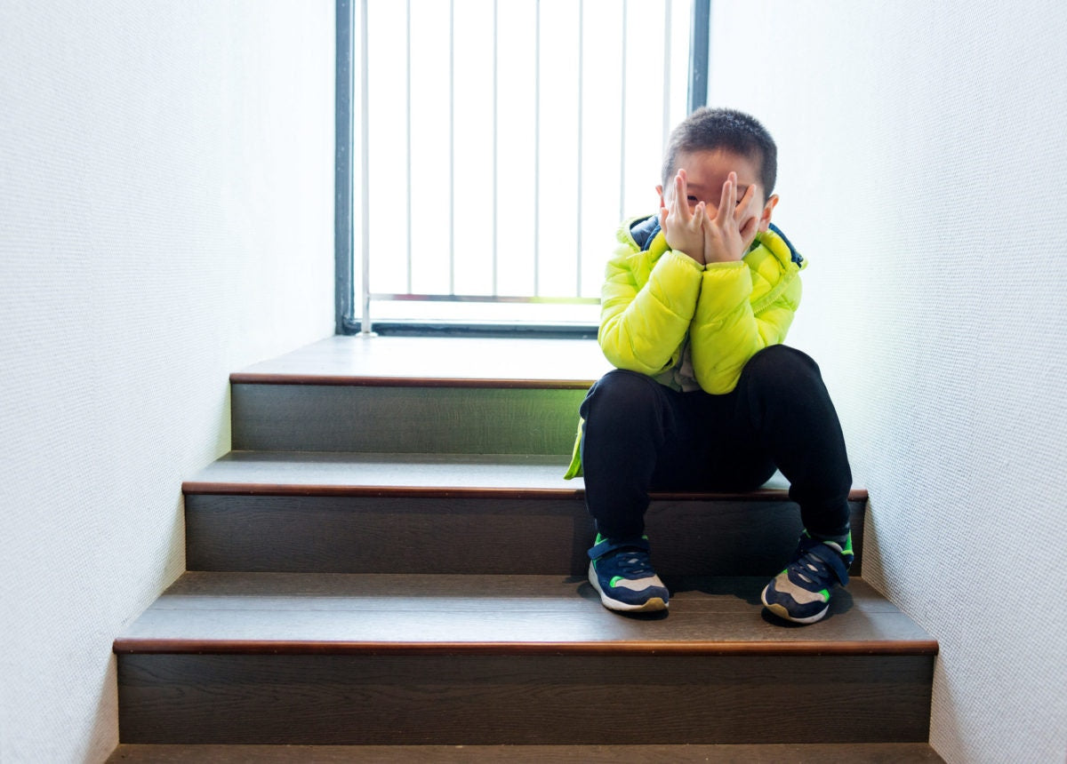 little boy with hands on face sitting on steps and smiling