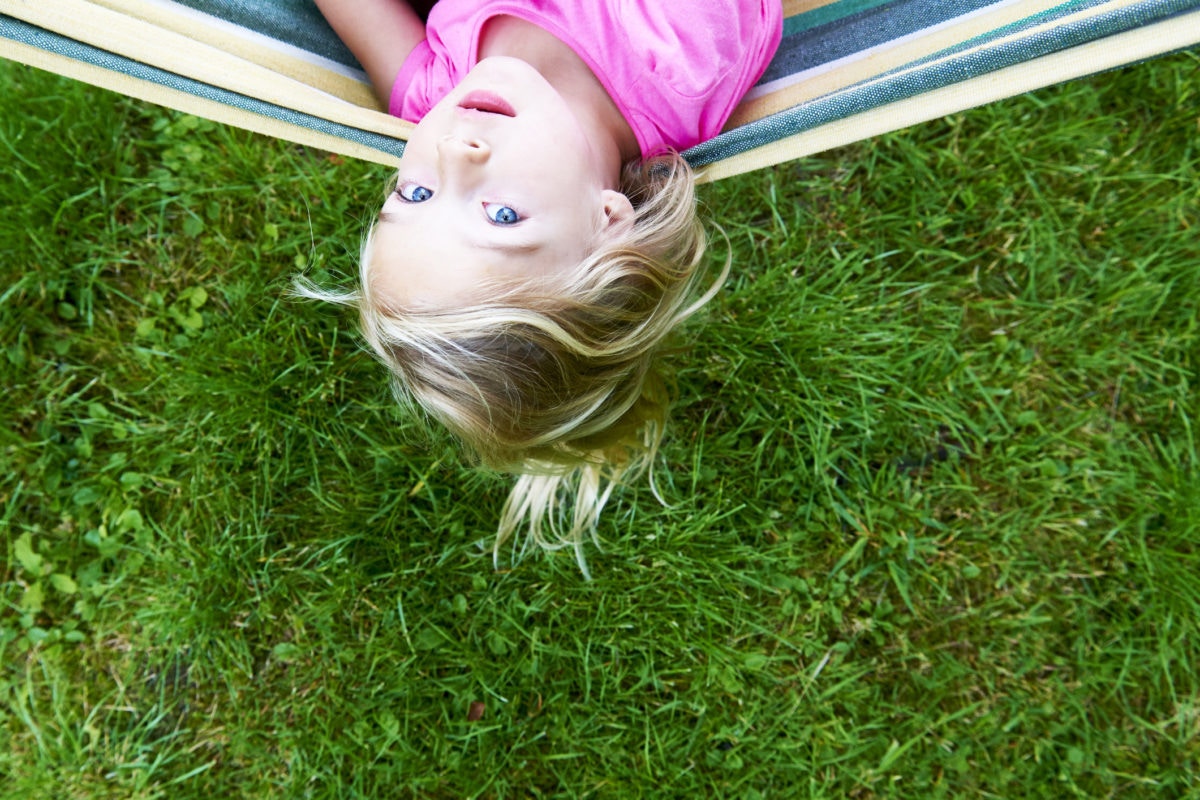 girl lying on colorful hammock at the garden looking at camera