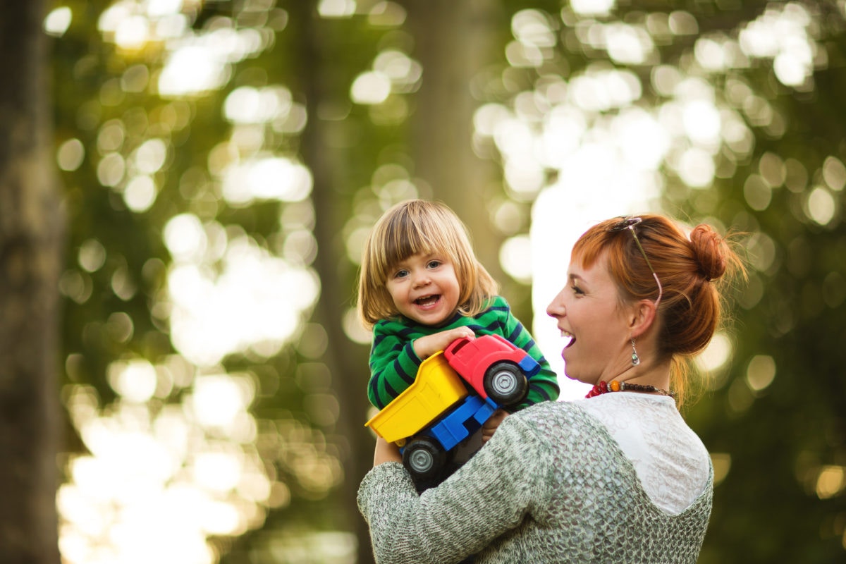 mother holding a young boy holding a toy