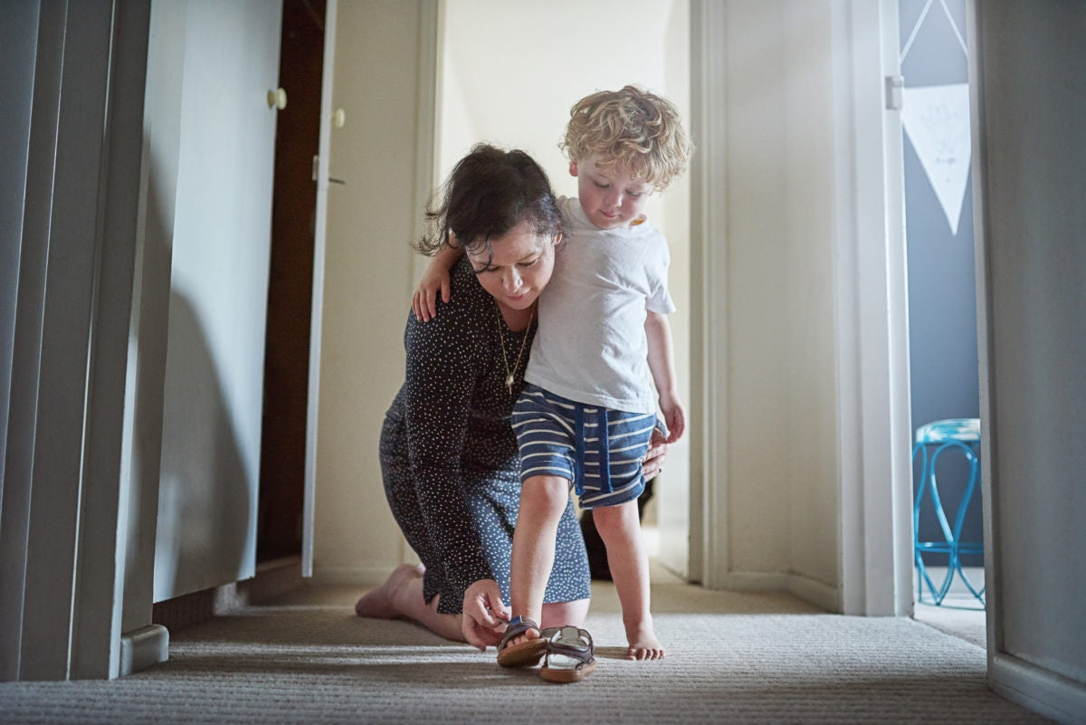 Mother helping her son to wear a shoes