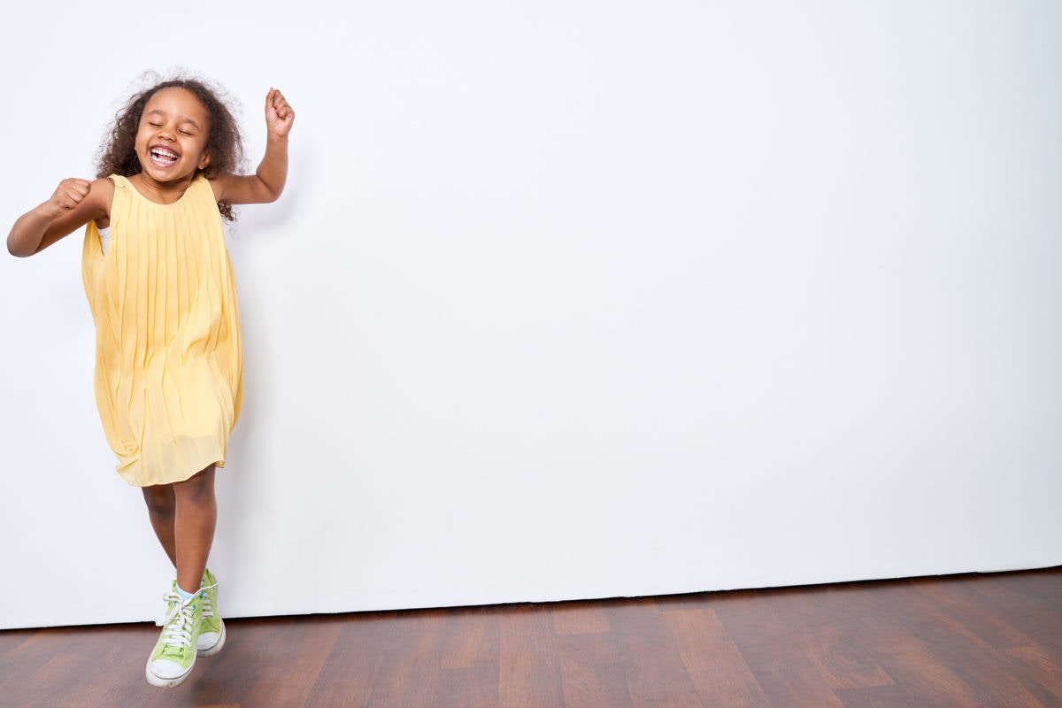 happy excited young girl in yellow dress laughing and jumping in the air