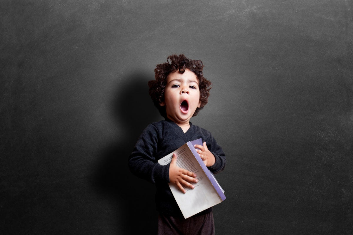 cute little girl yawning and holding a book