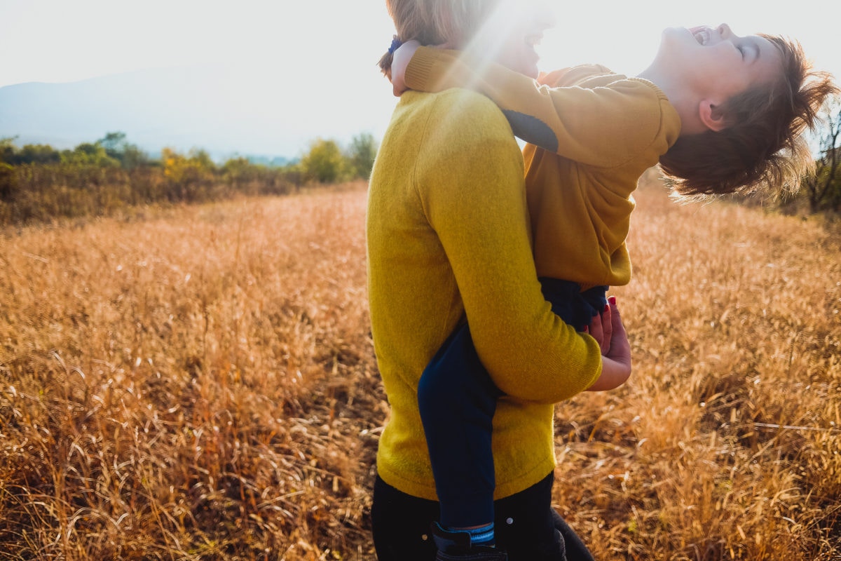 Mother holding kid boy on arms on wheat field in summer