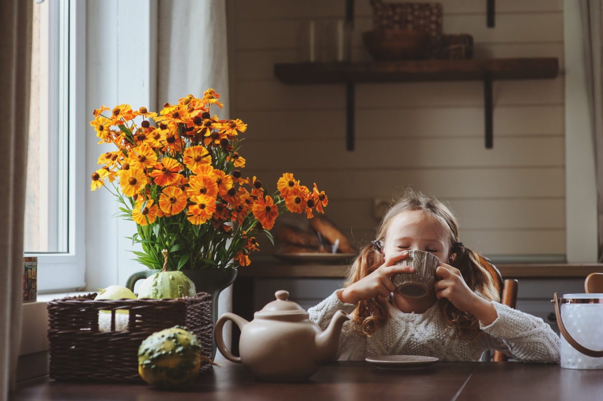 girl at kitchen table drinking tea