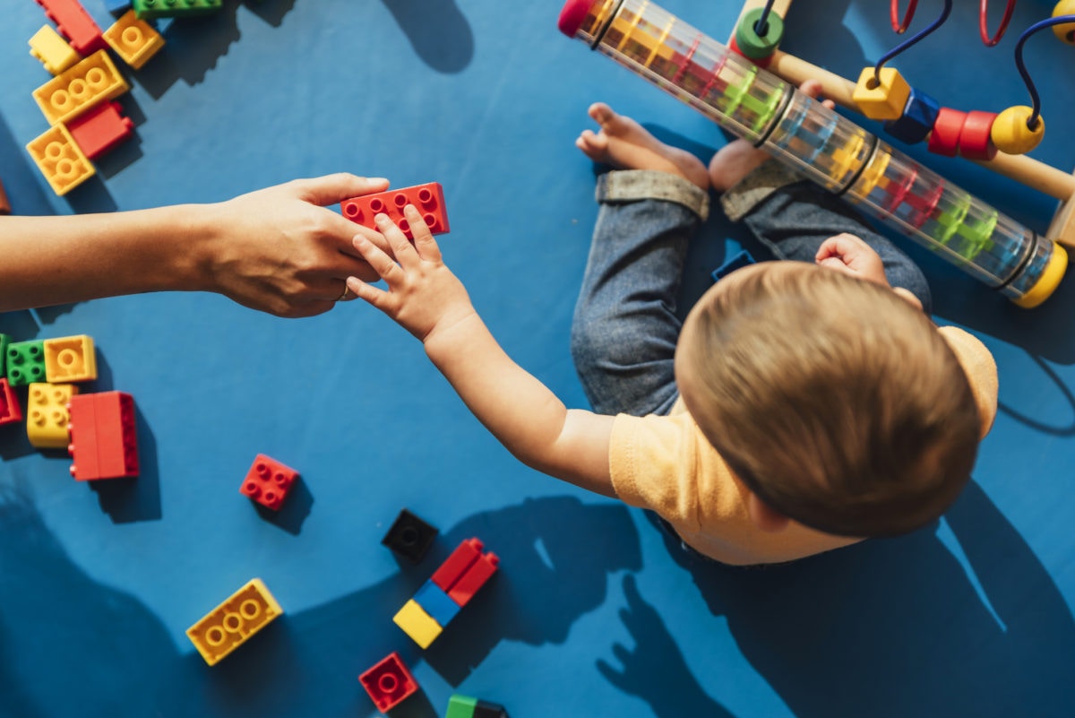 person handing a child a building block 