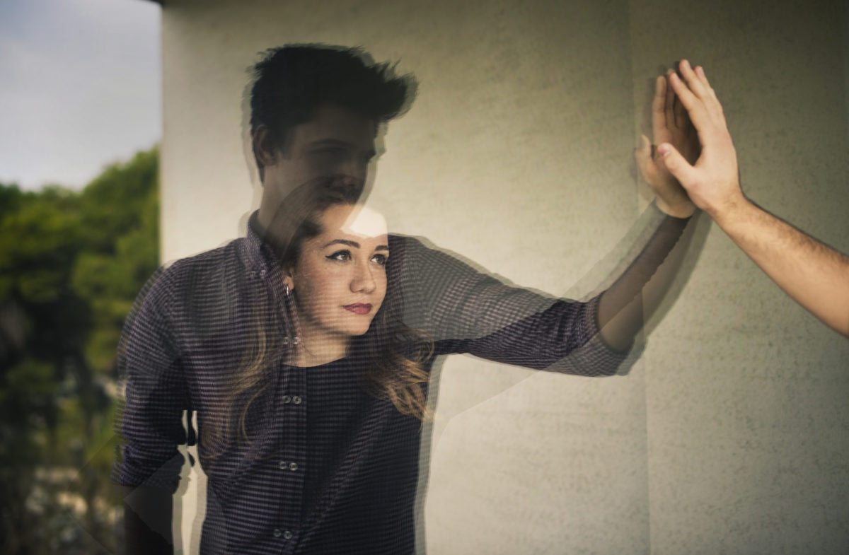 man and woman looking at each other through glass