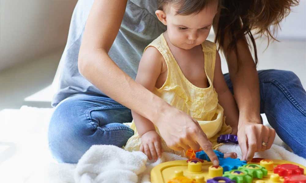 mère et fille jouant avec un jouet sur le sol