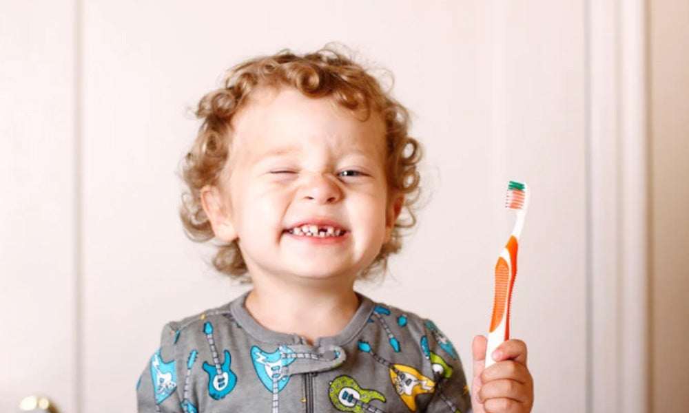 boy shows his teeth and toothbrush