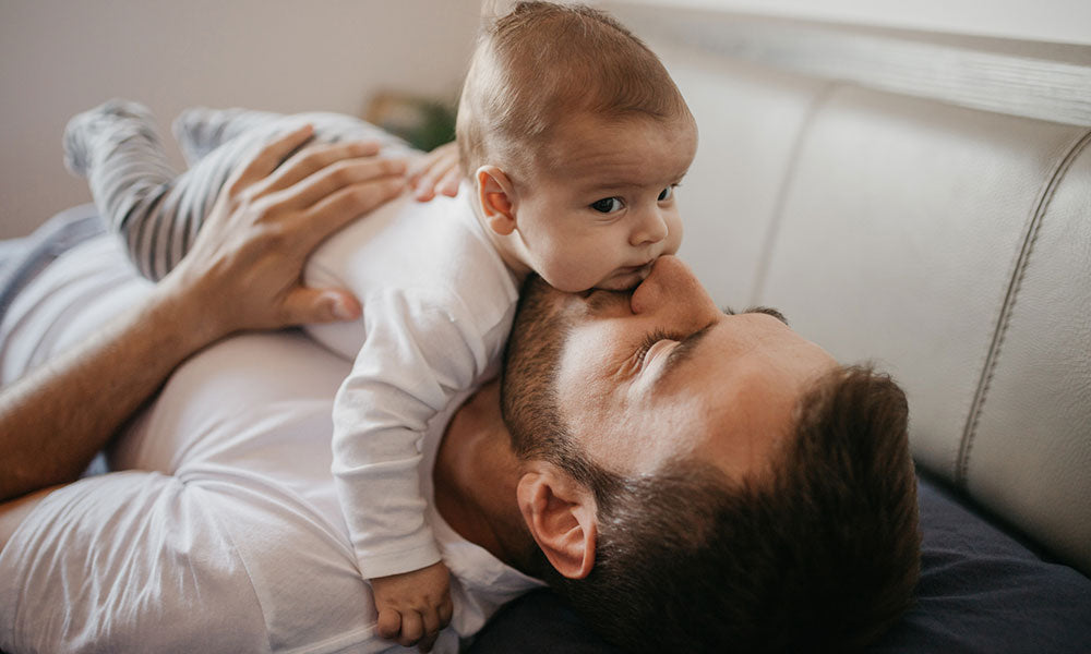 father playing in bed with his little baby