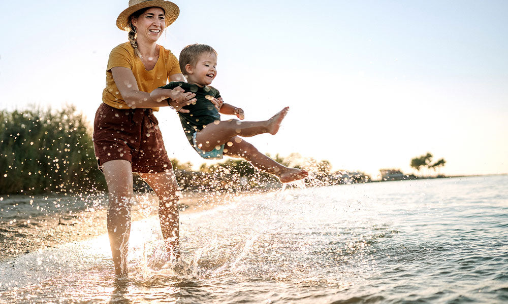 little boy having fun in the sea while being held by his mother