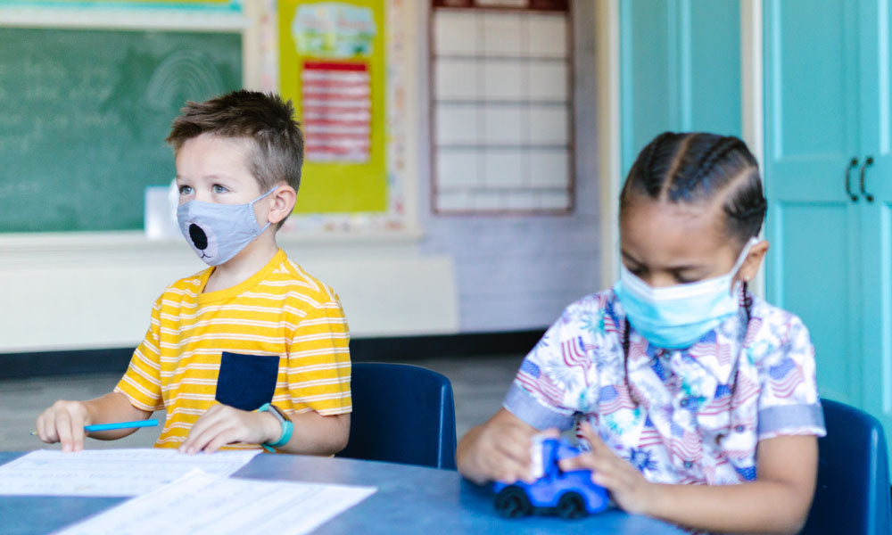 two kids at a desk wearing masks